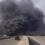 Photo: The smoke rises while the members of the Syrian forces travel in a vehicle in Latakia