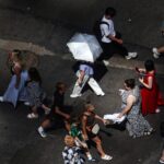 Photo: pedestrians, including a person holding an umbrella to block UV rays, walk on Times Square in New York