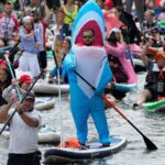 Photos show costumed participants steer stand-up paddle boards at a festival in Russia