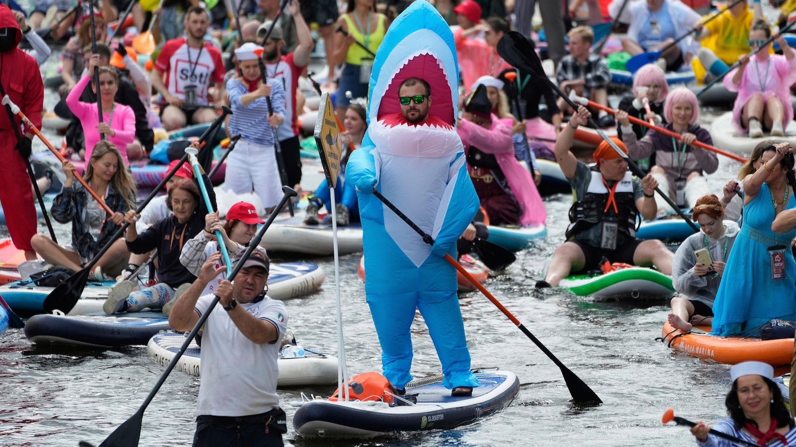 Photos show costumed participants steer stand-up paddle boards at a festival in Russia